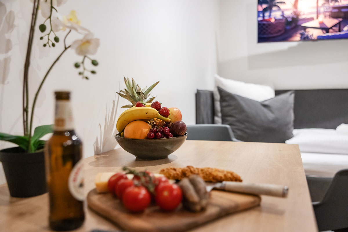 Moderne Küche mit Obstschale, Brett mit Brot und Bierflasche, warm beleuchtet.