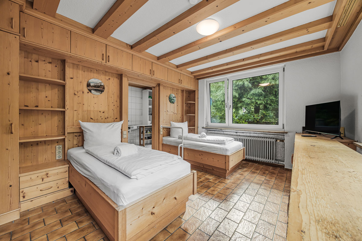 Gemütliches Schlafzimmer mit zwei Einzelbetten, Holzverkleidung und Fenster.