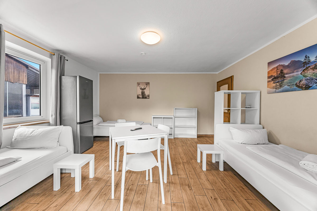 Helles Wohnzimmer mit Holzboden, weißen Möbeln, Kunst an der Wand.