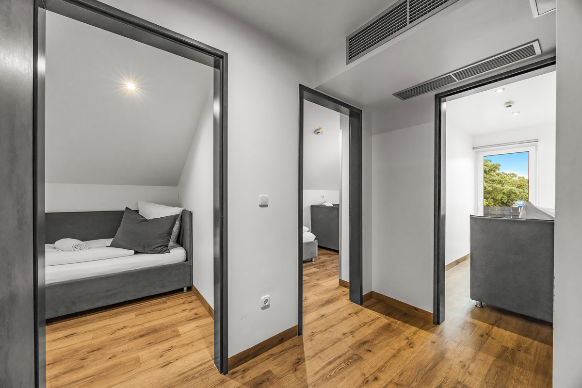 Helles modernes Zimmer mit Holzboden, zwei offenen Türen und Dachfenster.