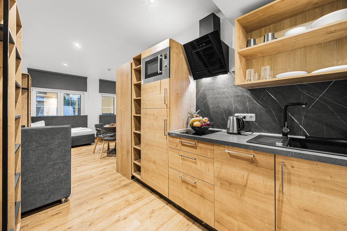 Eine moderne Küche mit Holzschränken und schwarzer Arbeitsplatte.