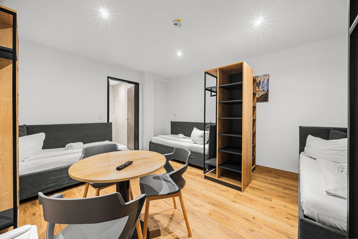 Ein modernes, minimalistisches Wohnzimmer mit Holzboden und drei Betten.