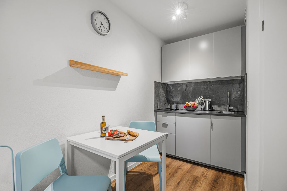 Kleine moderne Küchenzeile mit grauen Schränken und Holzfußboden.