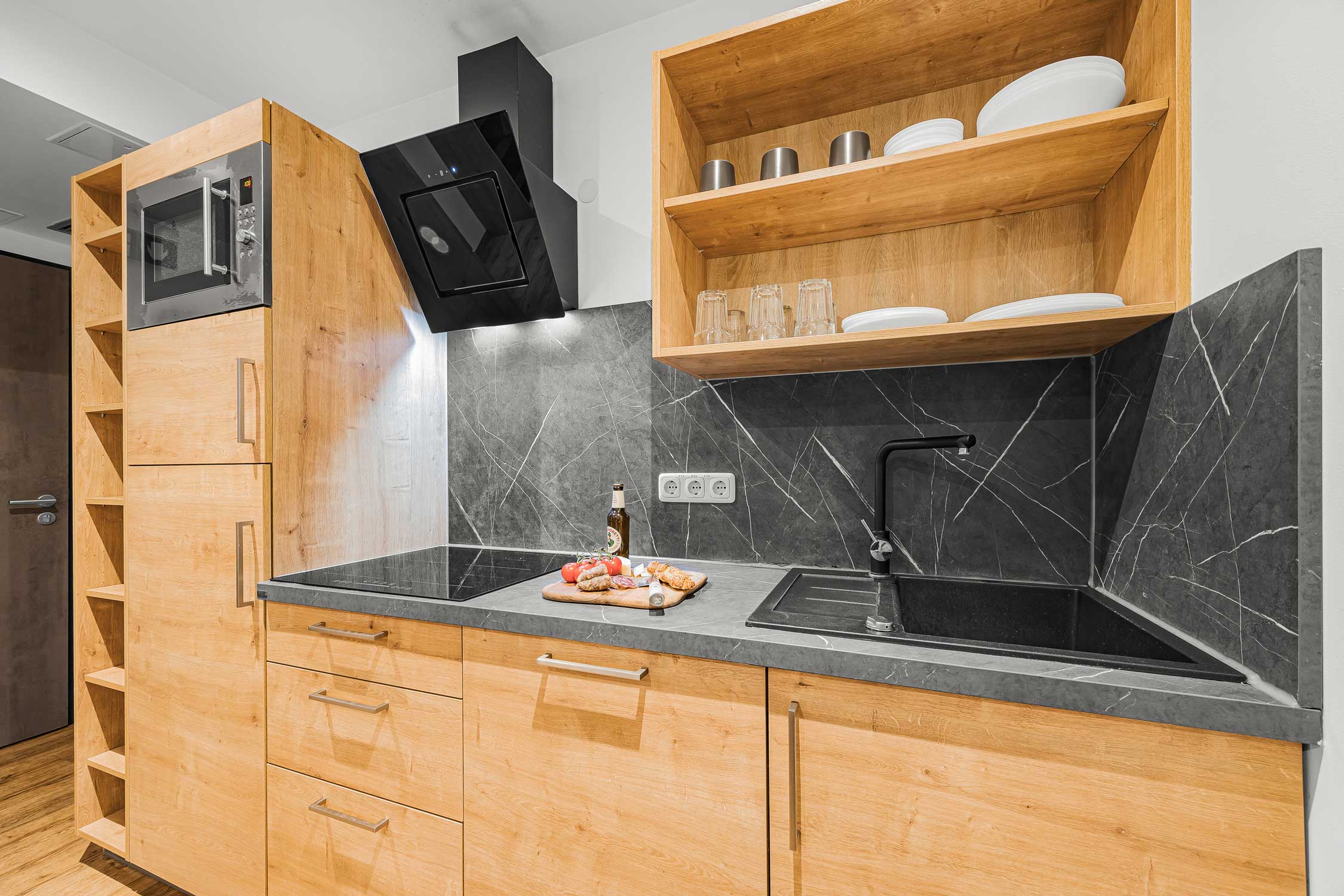 Moderne Holzküche mit schwarzer Stein-Arbeitsplatte und Edelstahlauszug.