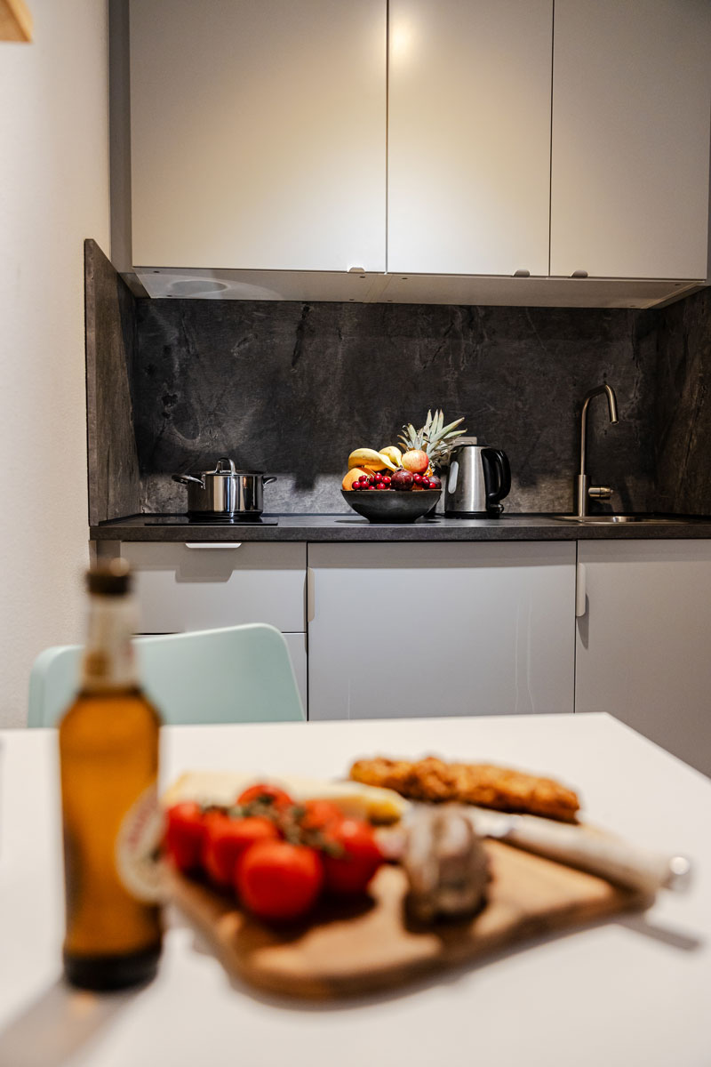 Moderne Küche mit Obstschale, Bierflasche und Teller mit Tomaten vorne.