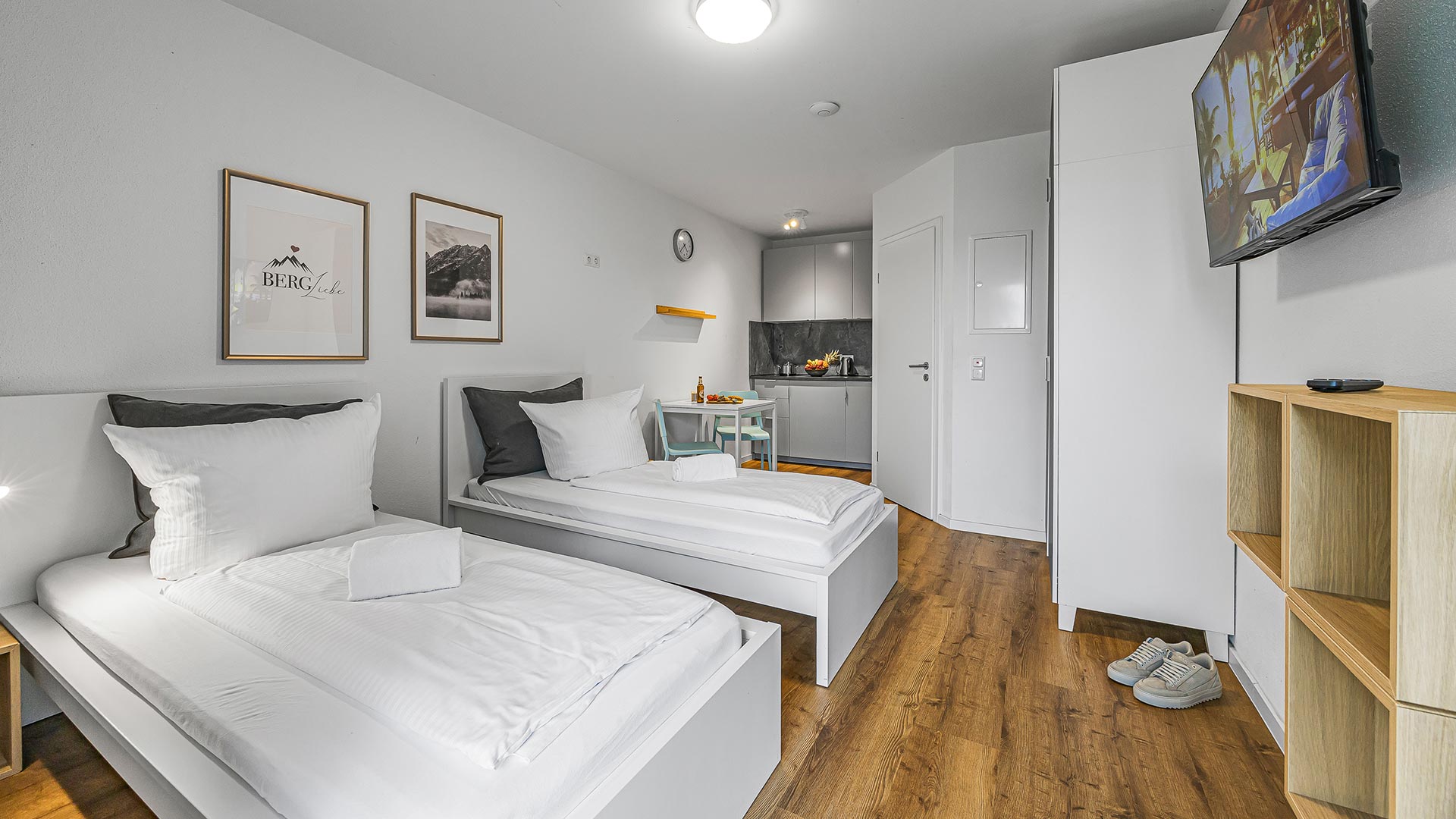 Ein modernes, helles Schlafzimmer mit zwei Einzelbetten in minimalistischer Einrichtung.