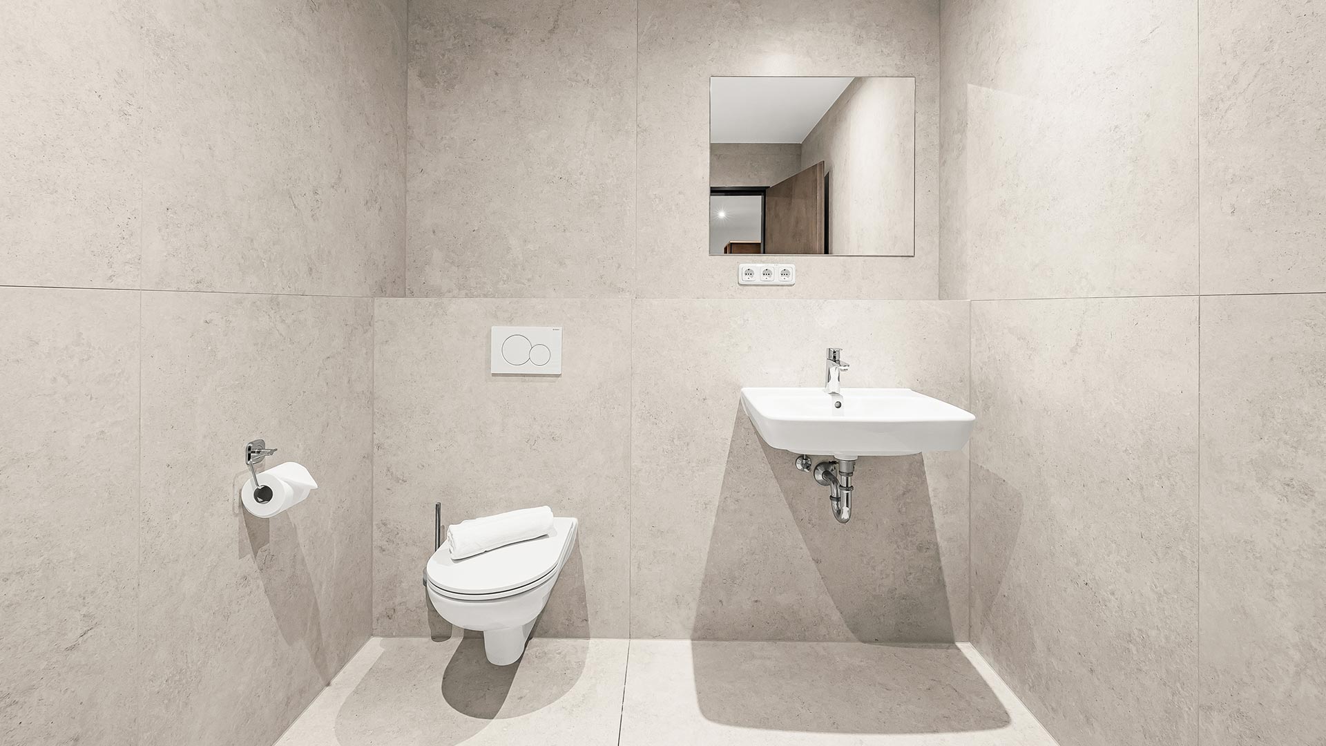 Ein minimalistisches Badezimmer mit weißen Sanitäranlagen und rechteckigem Spiegel