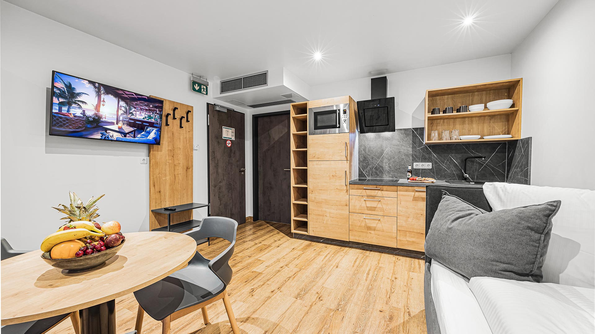 Eine moderne Küche mit Holzboden, grauen Akzenten und Obstschale auf dem Tisch