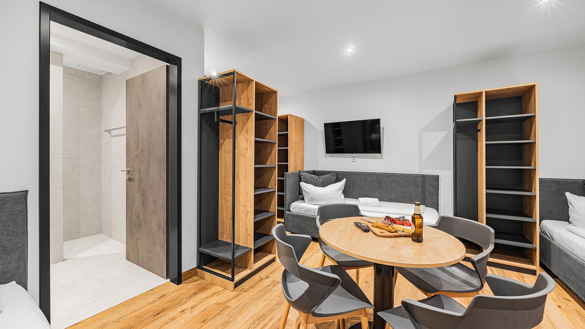 Helles, modernes Wohnzimmer mit Holzböden, Tisch und grauen Stühlen im minimalistischem Stil