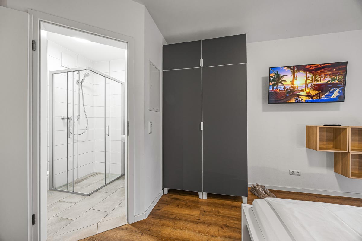 Ein modernes Schlafzimmer mit grauem Kleiderschrank und hellem Holzboden.