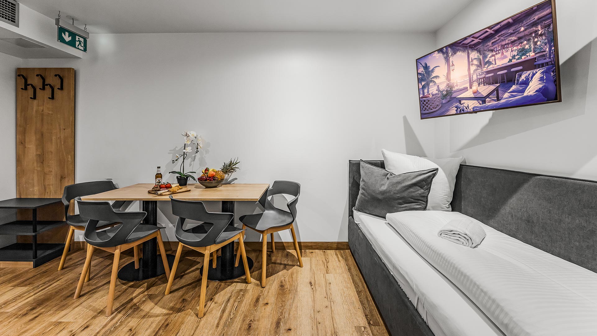 Ein modernes Zimmer mit hellbraunen Holzböden, grauen Möbeln und einem gemütlichen Sofa.